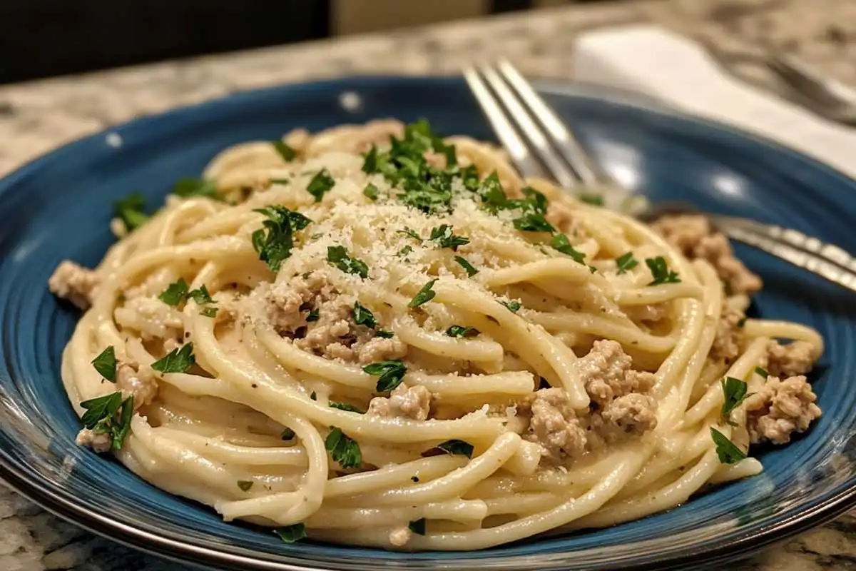 Ground chicken being cooked in a skillet for Alfredo pasta