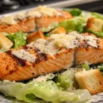 Close-up of a fork lifting a bite of Salmon Caesar Salad.