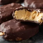 Creamy peanut butter frozen yogurt bars coated in rich chocolate glaze on a dark background.