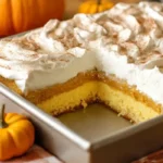 Pumpkin magic cake in a baking pan with layers of pumpkin filling, yellow cake, and whipped cream topping